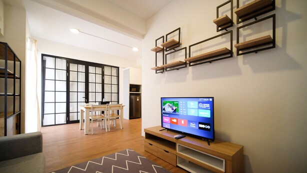 Una sala de estar moderna con un televisor de pantalla plana, muebles de madera y un puerta corrediza.
