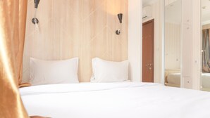 A hotel room with a large bed, two wall-mounted lights, and a wooden headboard. - Nice And Homey 2Br Signature Park Grande Apartment (Jakarta)