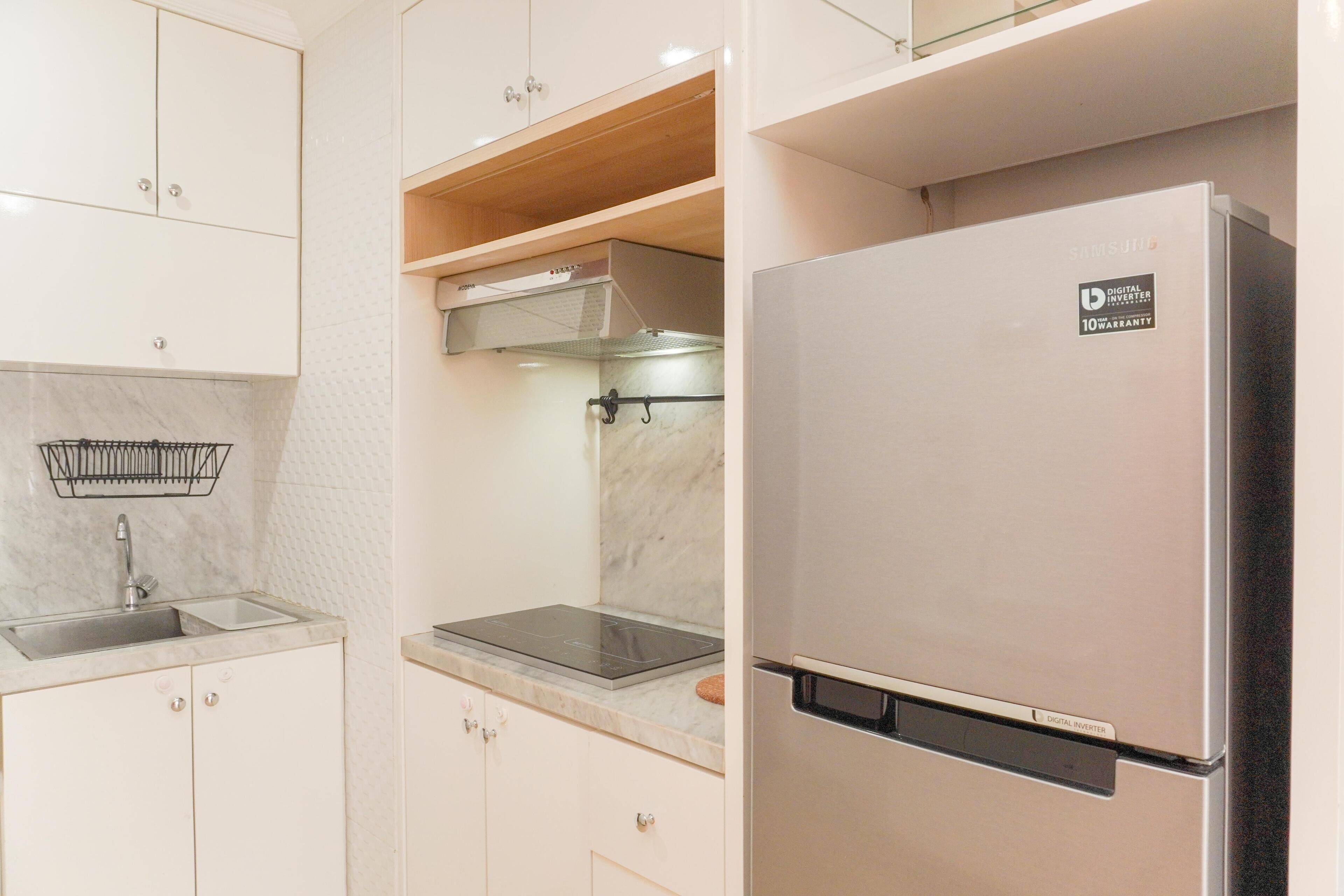 Eine moderne Küche mit weißen Schränken, einem Edelstahl-Kühlschrank, einem Einbauofen und einer Marmorarbeitsplatte.