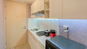 Una cocina compacta con un lavamanos, un hervidor y una tostadora.