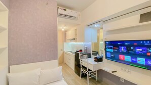 Una habitación de hotel moderna con cama, escritorio con computadora y televisor de pantalla plana mostrando varias aplicaciones.