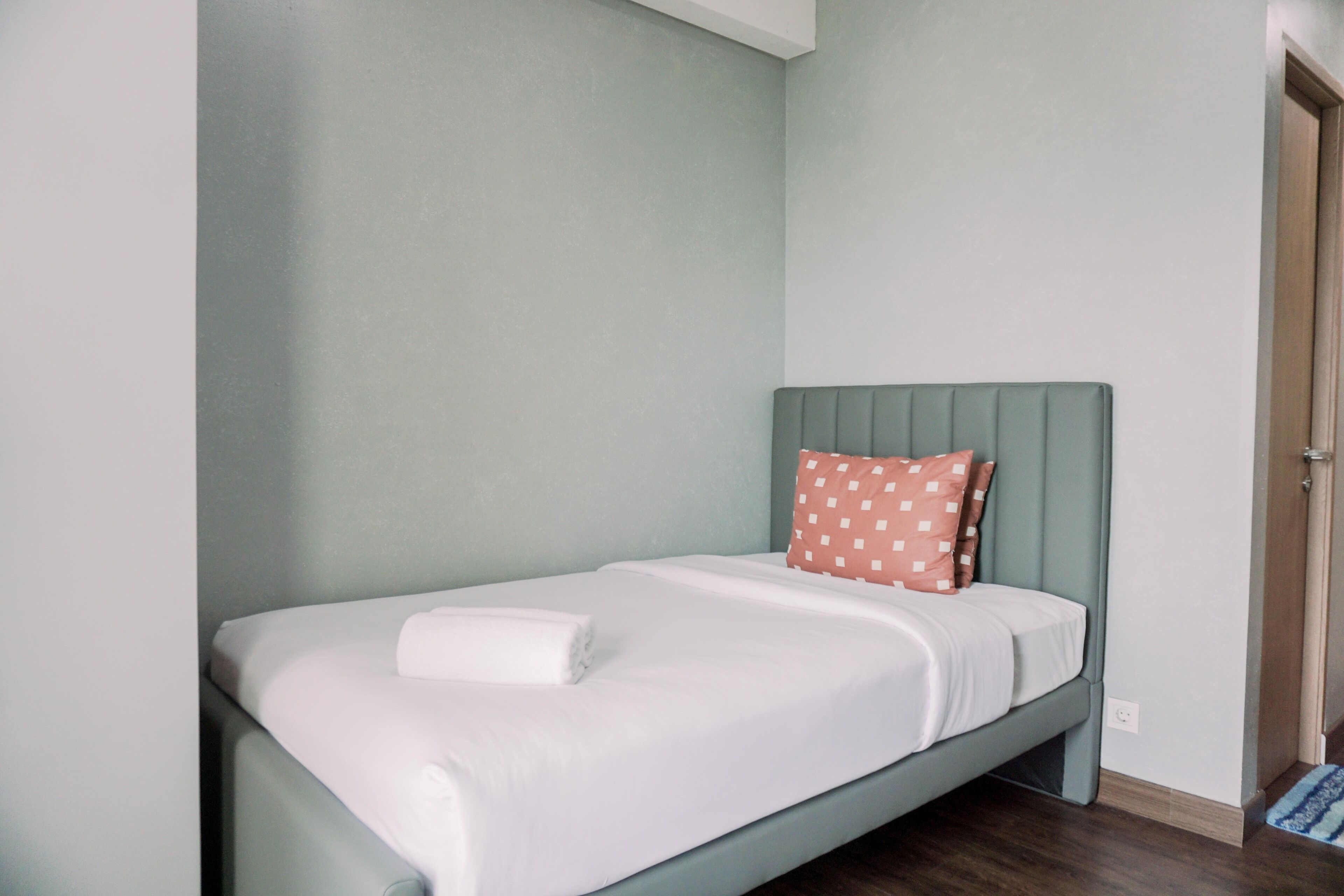 Un lit simple avec une tête de lit, un oreiller et une couverture soigneusement disposée.