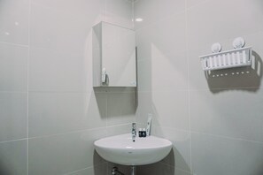 A bathroom with a white sink, a mirror, and a white towel rack. - Simply And Cozy Stay Studio Apartment B Residence (Pagedangan)