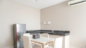 Eine moderne Küche mit einem Edelstahlkühlschrank, einer schwarzen Arbeitsplatte und einem weißen Esstisch mit vier Stühlen.