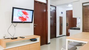 Een hotelkamer met een aan de muur bevestigde televisie, een houten tafel en een klein zithoekje.