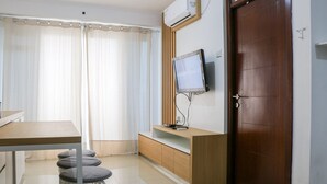 Een moderne kamer met een houten bureau, een aan de muur bevestigde televisie en een deur.