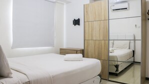 Een slaapkamer met een bed, nachtkastje, kledingkast en een airconditioning.
