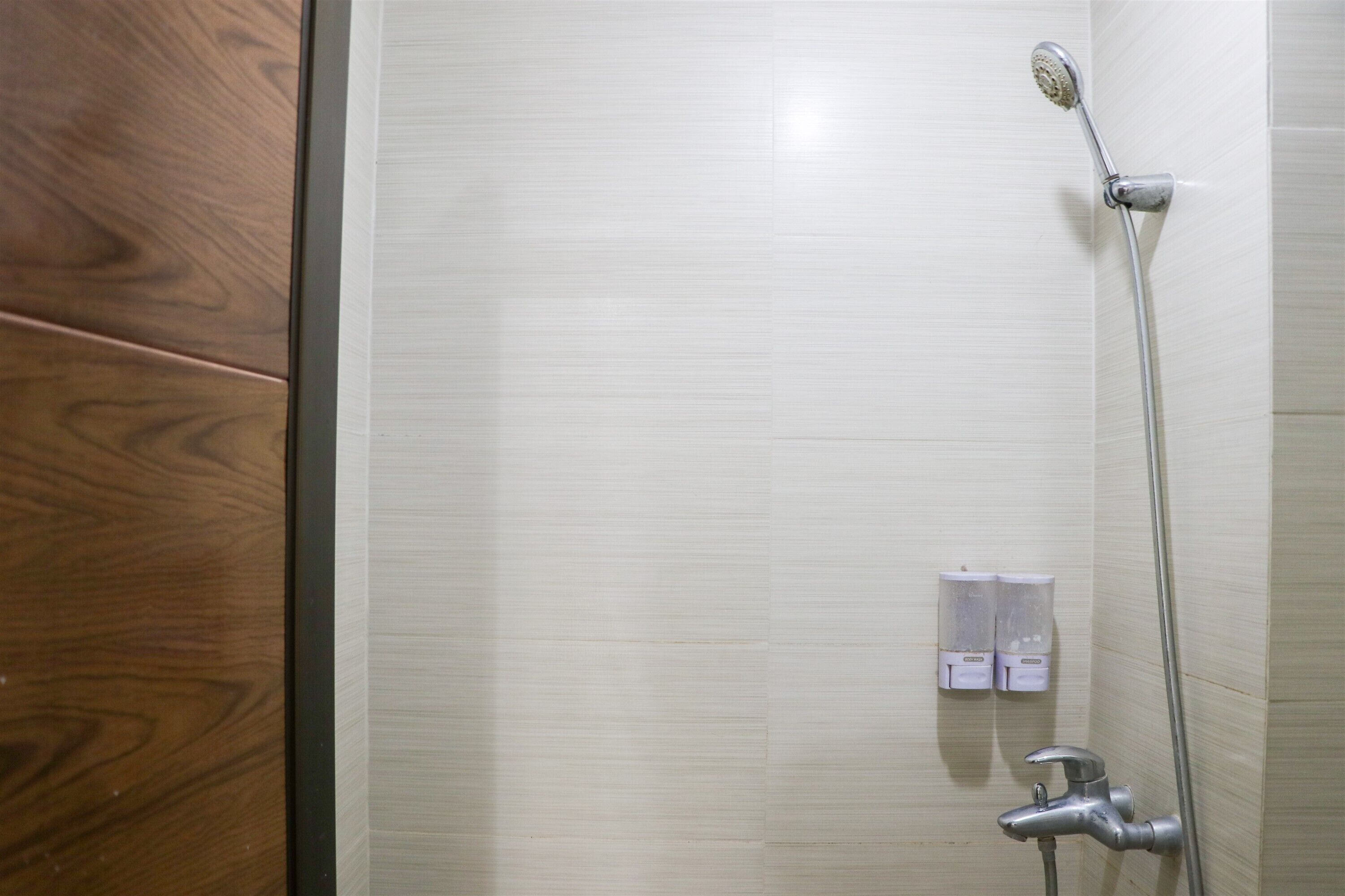 A bathroom with a shower, a toilet, and a wooden door.