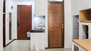 Een compacte keuken met een houten deur, een spoelbak en een klein aanrecht.
