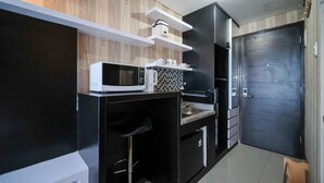 Una cocina compacta con microondas, cafetera y un lavamanos pequeño.