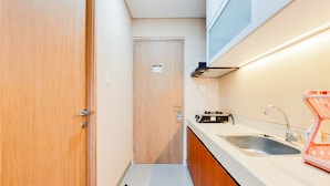 Cozinha compacta com porta de madeira, pia e bancada.