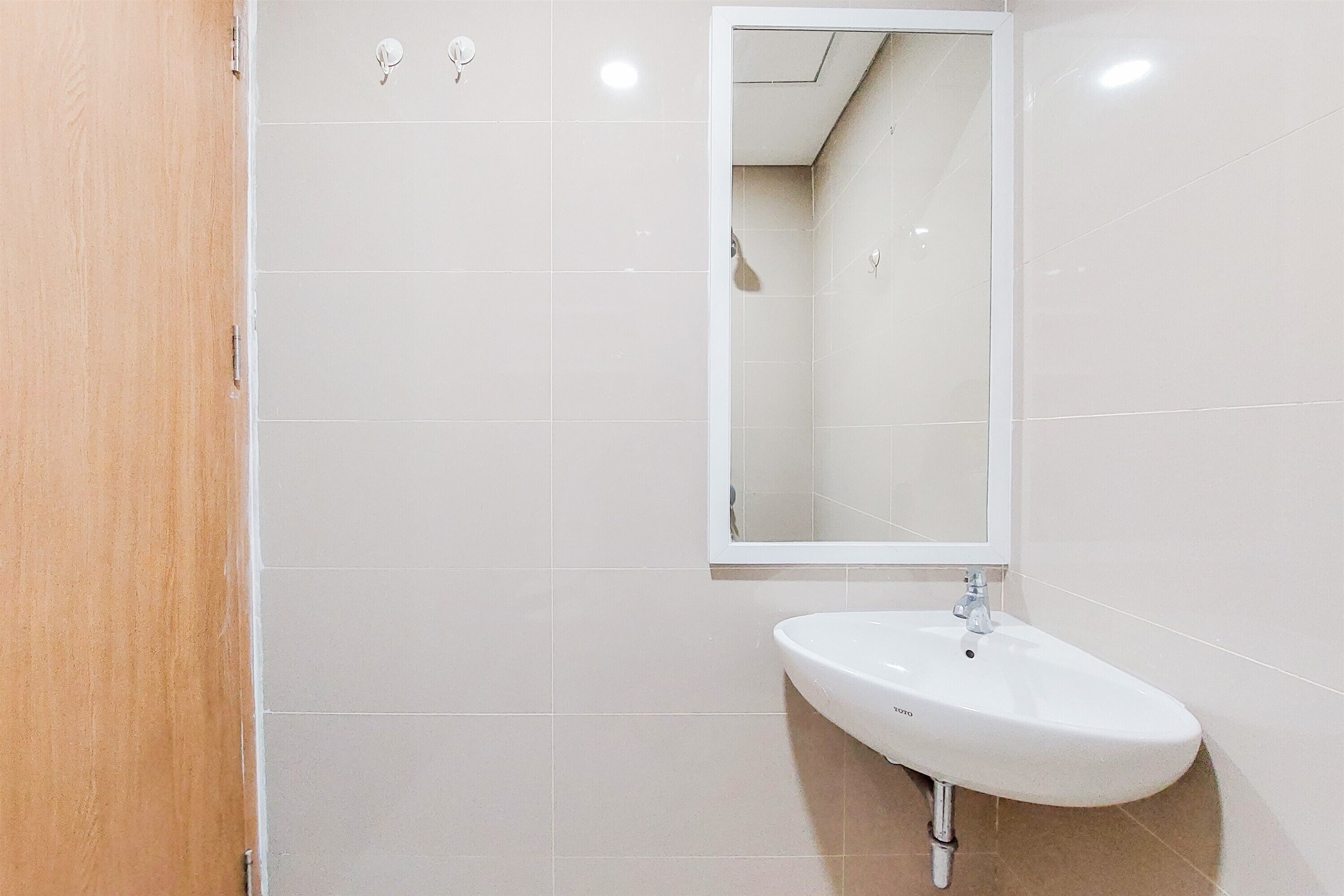A bathroom with a white sink, a mirror, and a wooden door.