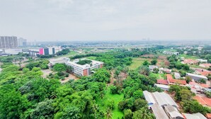 Um edifício grande com vários andares, rodeado por vegetação exuberante e algumas estruturas menores.
