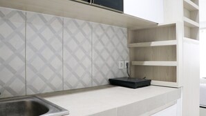 Een keuken met een rvs-spoelbak, witte kasten en een decoratieve spatwand.
