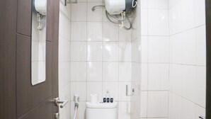 Een moderne badkamer met witte tegels, een toilet, een handdroger en een papieren handdoekdispenser.