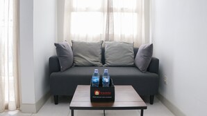 Een moderne woonkamer met een grijze bank, twee kussens en een tafel met een doosje gratis etenswaren en drankjes van Travelio.