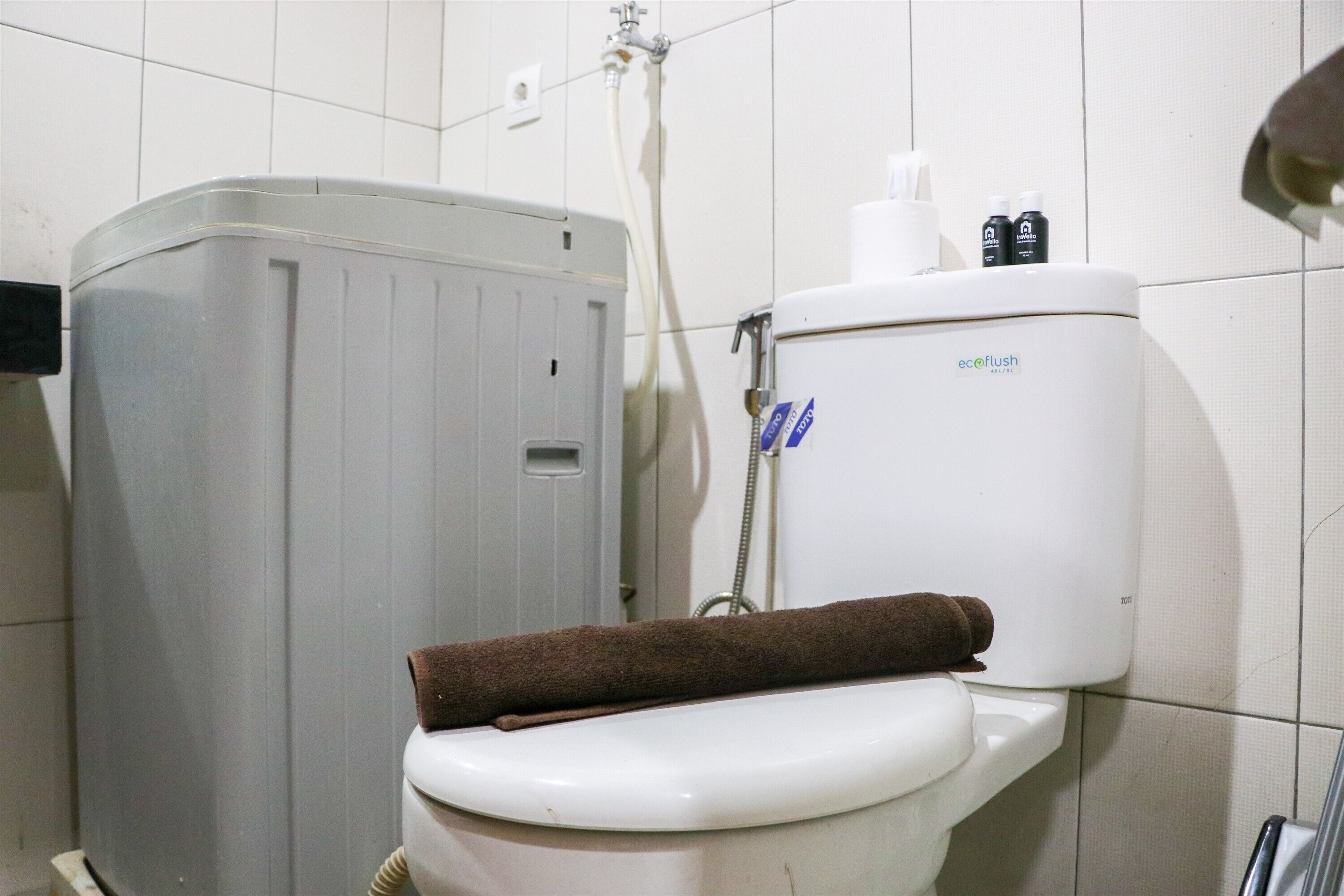Ein Badezimmer mit Toilette, Waschmaschine in Grau und Duschkabine.