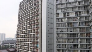 Un immeuble résidentiel de grande hauteur, doté de nombreux balcons, d’un noyau central et d’un bâtiment de style traditionnel en premier plan.