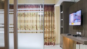 Un espace d’accueil moderne, doté d’un comptoir de réception en bois, d’un téléviseur à écran plat fixé au mur et d’un rideau décoratif en bambou.