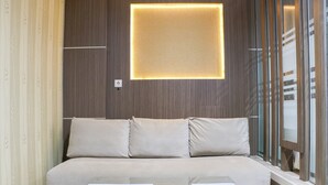 Une pièce moderne avec un canapé, une table basse en verre et un luminaire fixé au mur.