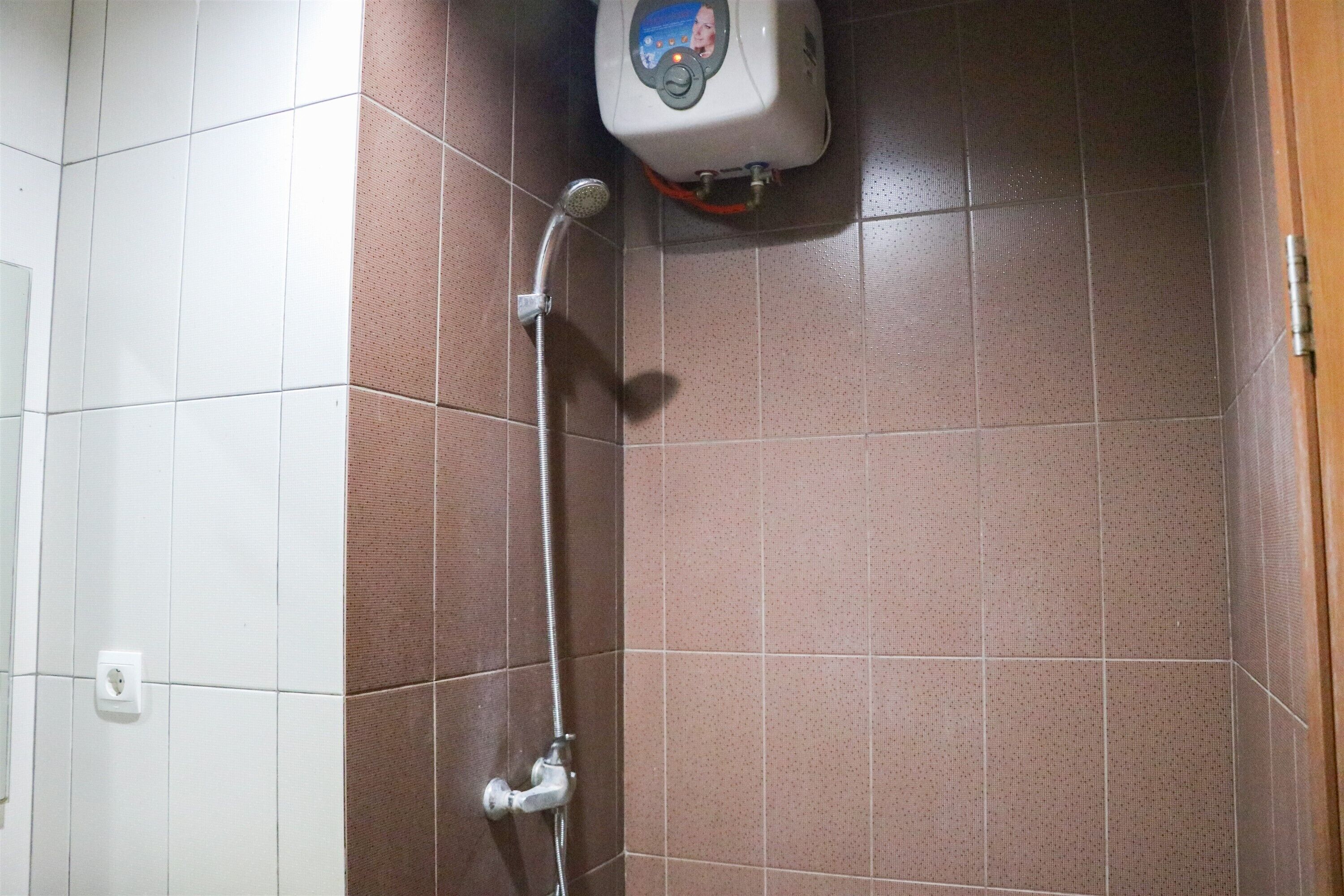 Un espace douche équipé d’un pommeau de douche à main et d’un panneau de commande fixé au mur.