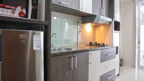 Une cuisine moderne dotée d’appareils électroménagers en acier inoxydable, de meubles en bois et d’un four à micro-ondes encastré.