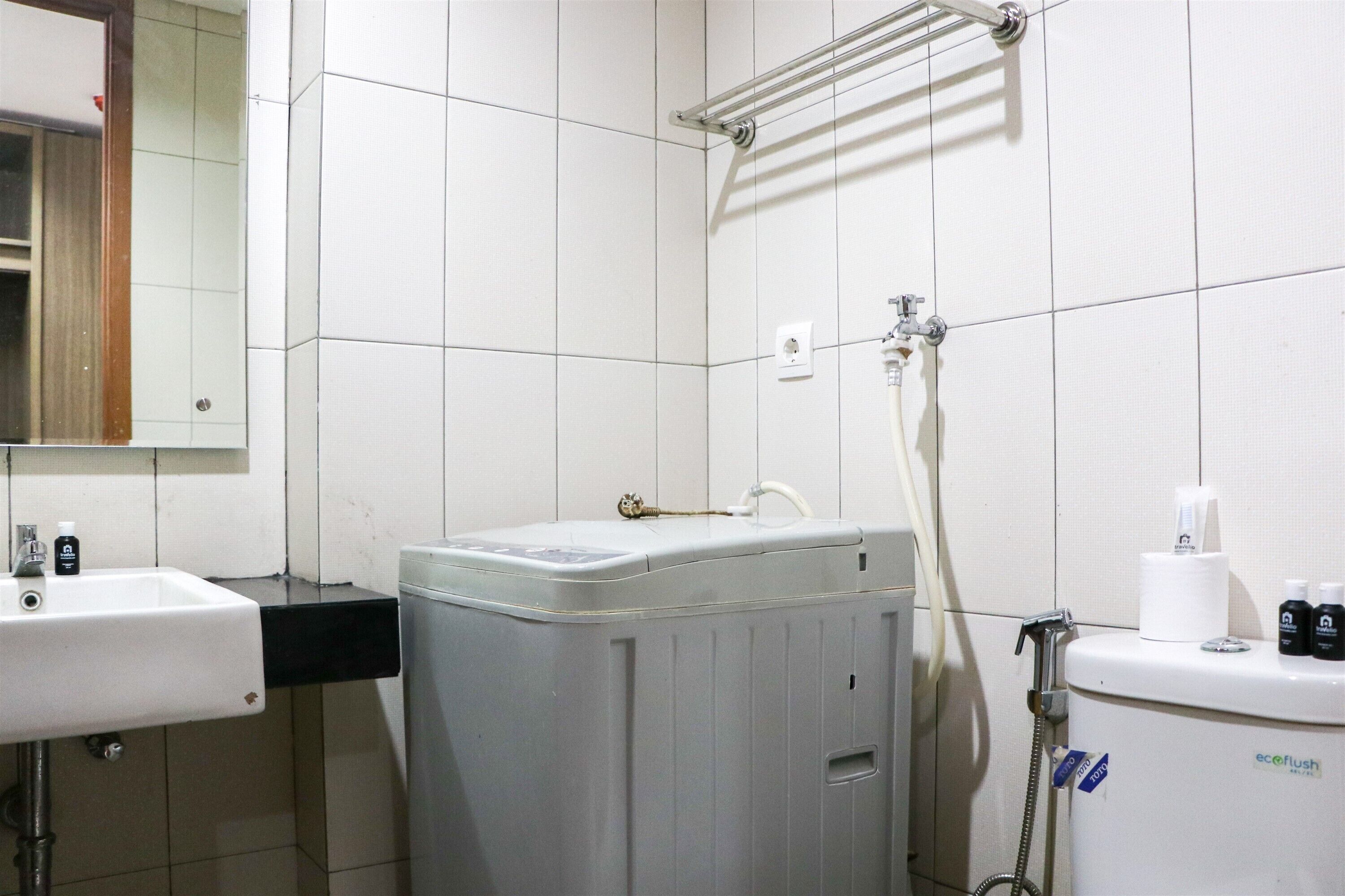 A bathroom with a white sink, a washing machine, and a toilet.