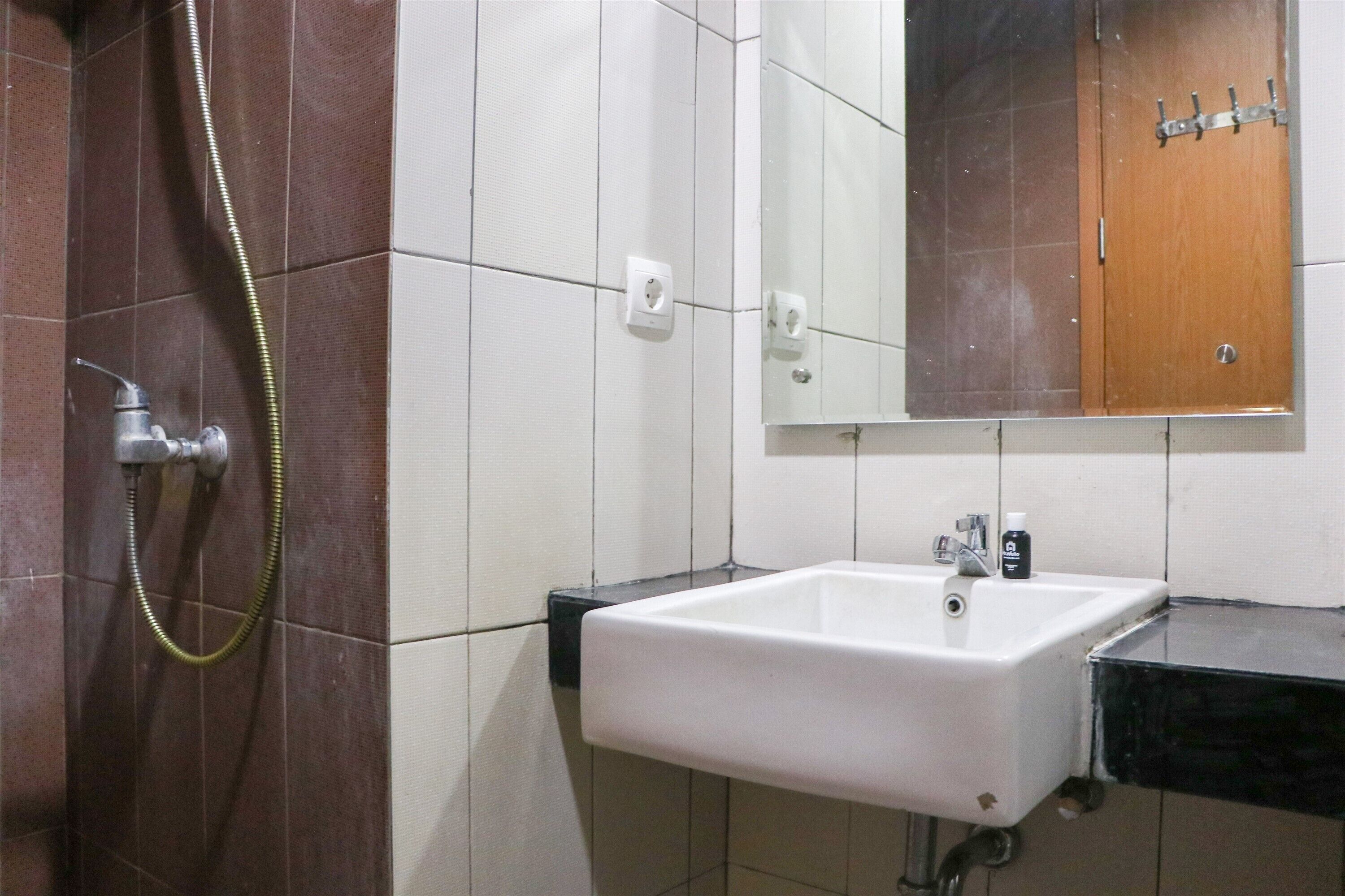 Un bagno con un lavandino bianco, uno specchio sopra e una doccia con il flessibile.