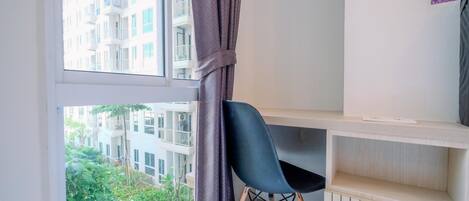 Una habitación moderna con un ventanal grande, una silla negra y un estante blanco.