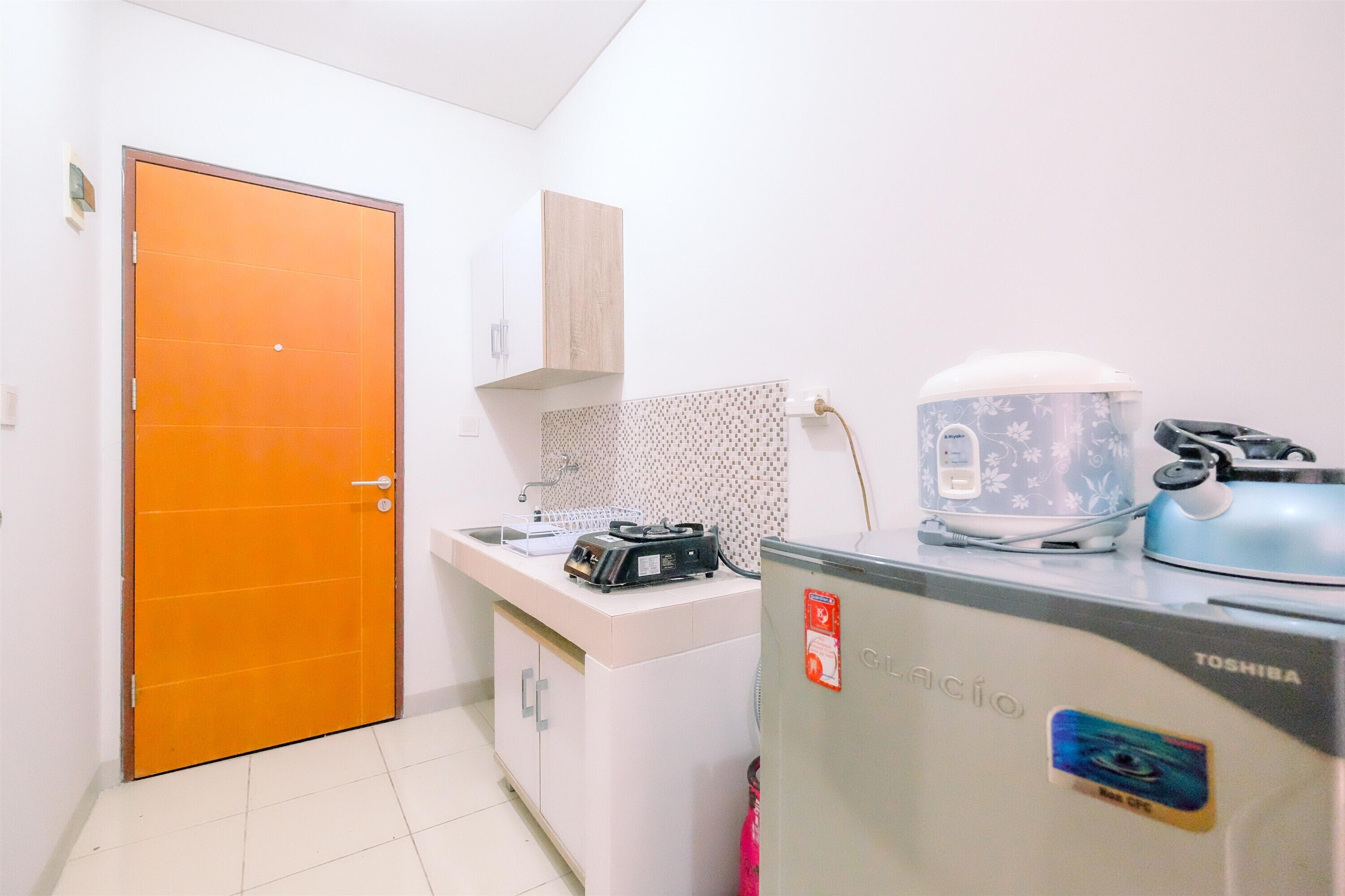 Una cocina funcional equipada con refrigerador, microondas, hervidor y tostadora.