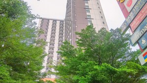A tall building with multiple balconies and a signboard with various advertisements. - Enjoy Living And Homey Studio Dave Apartment (Depok)