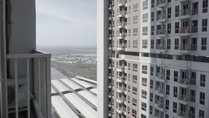 A high-rise building with multiple balconies, a clear view of the surrounding area, and a distant landscape. - Relax And Comfy Studio At Tokyo Riverside Pik 2 Apartment (Teluknaga)