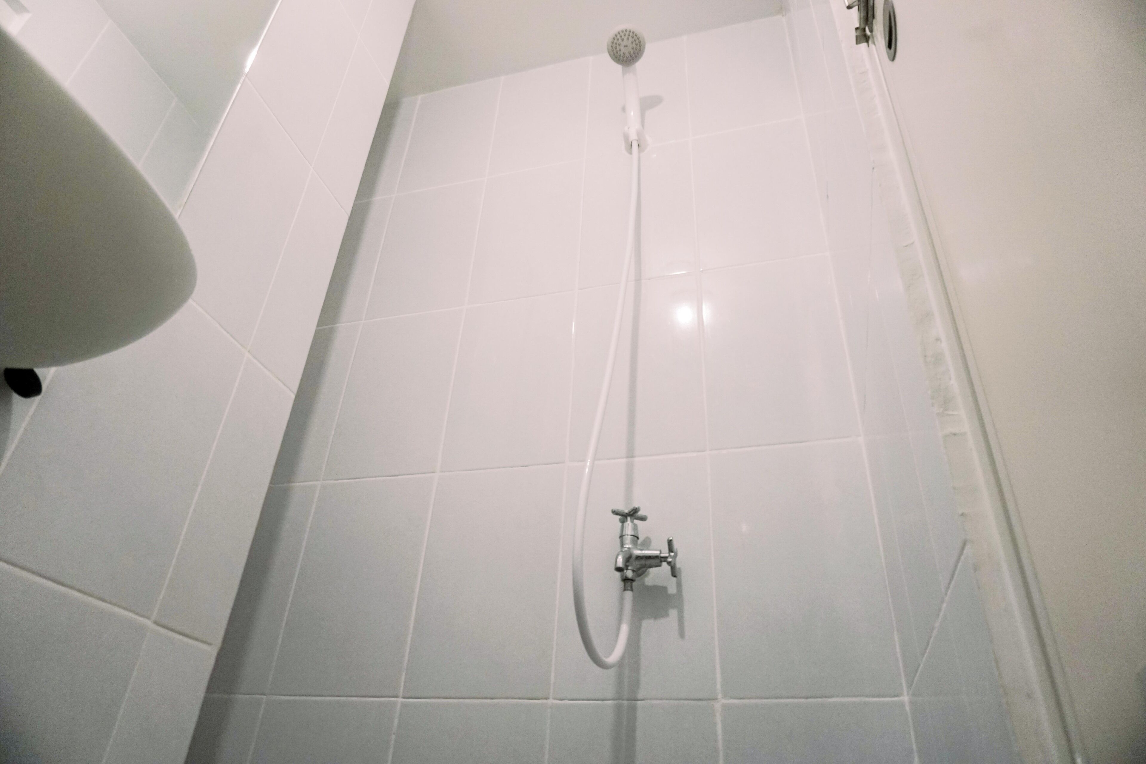 A shower with a handheld showerhead and a wall-mounted faucet.