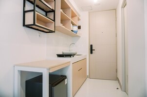 Cocina compacta con pileta, encimera y estanterías integradas.