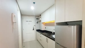 A compact kitchen with a refrigerator, a sink, and cabinets. - Good Choice And Modern Studio Marquis De Lafayette Apartment (Semarang)