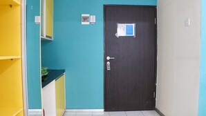 A room with teal walls, a dark wooden door, and a yellow counter. - Comfy Studio Apartment At Jarrdin Cihampelas (Bandung)