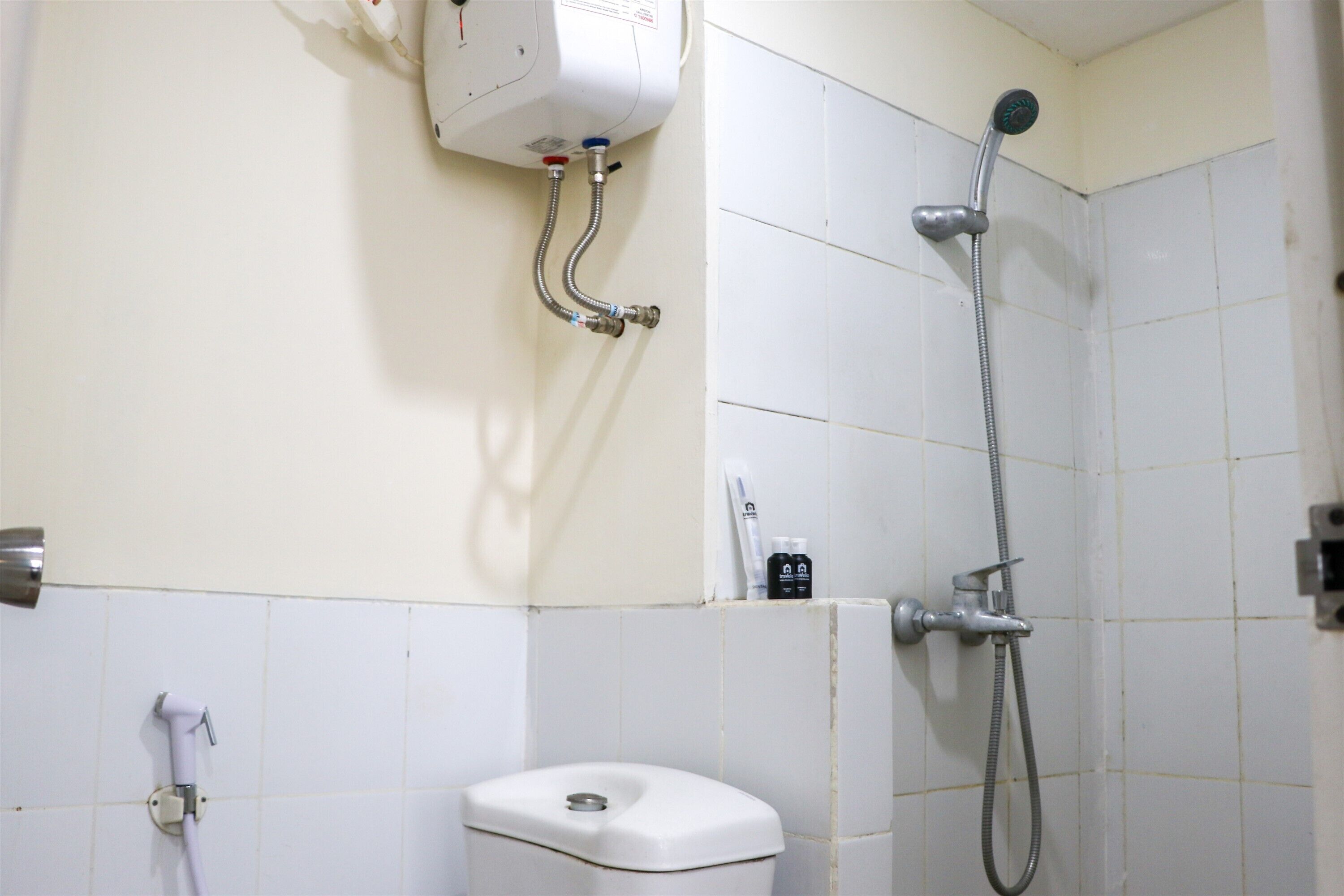 A bathroom with a toilet, a shower, and a water heater.
