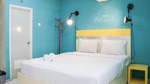 A bedroom with a bed, a bedside table, a wall-mounted lamp, and a door. - Comfy Studio Apartment At Jarrdin Cihampelas (Bandung)