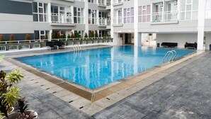 Una piscina rodeada por un edificio de varios pisos con balcones.