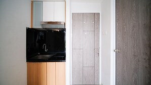 Una cocina con encimera negra, armarios de madera y una puerta doble con acabado en madera clara.