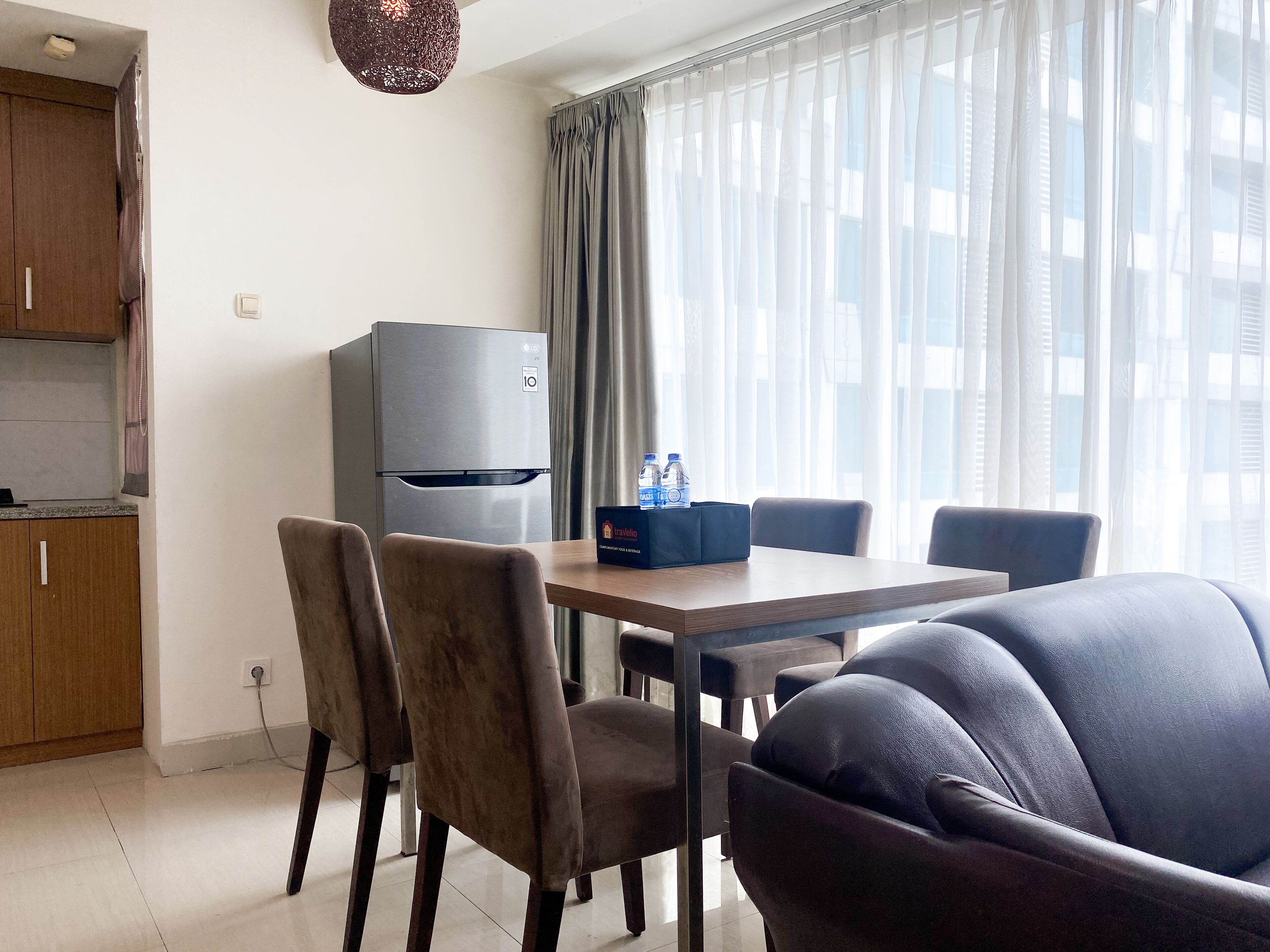Una habitación de hotel moderna con comedor, refrigerador y sofá.