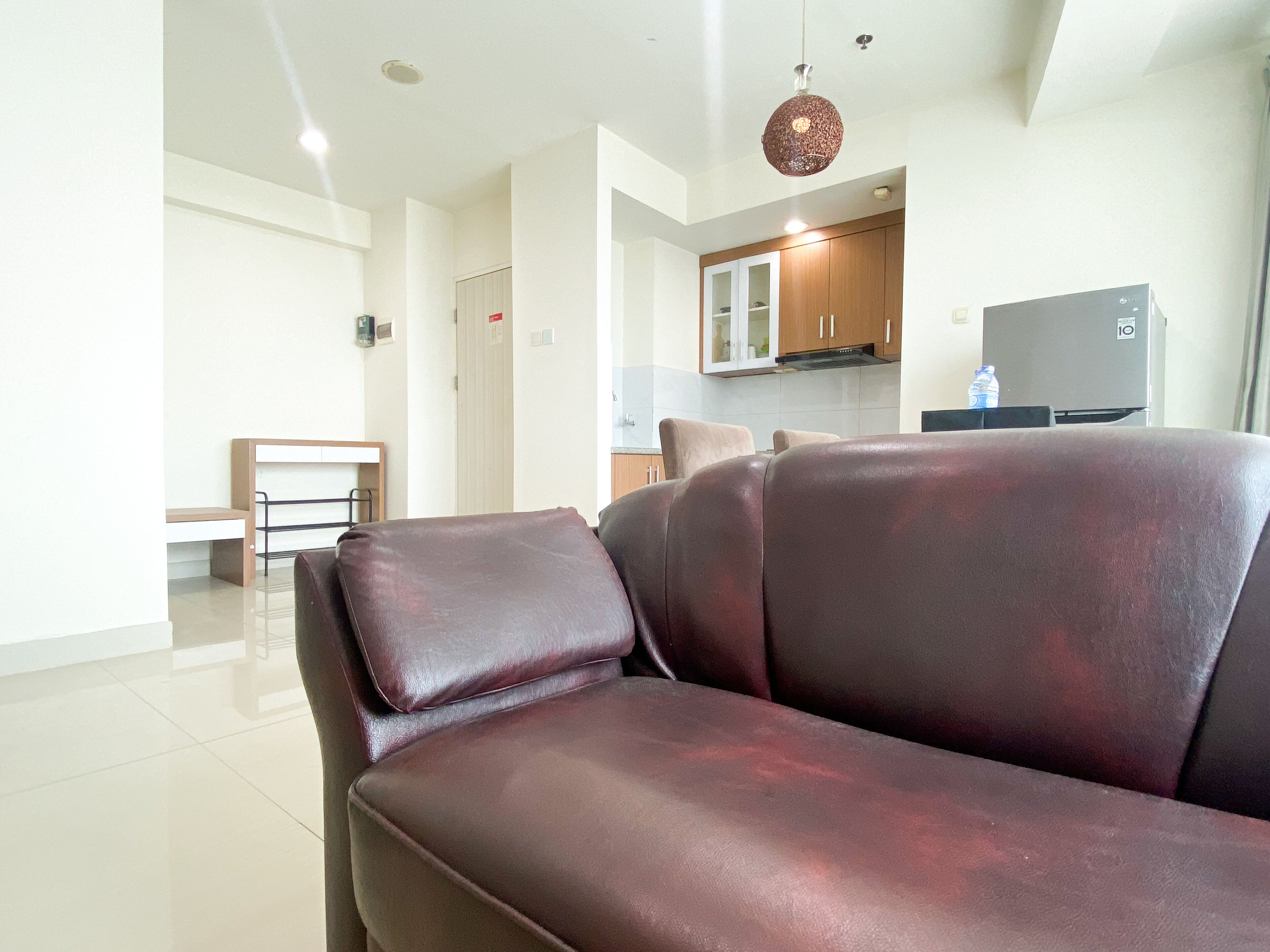 Una sala moderna con un sofá de cuero, un banco de madera y una cocina al fondo.