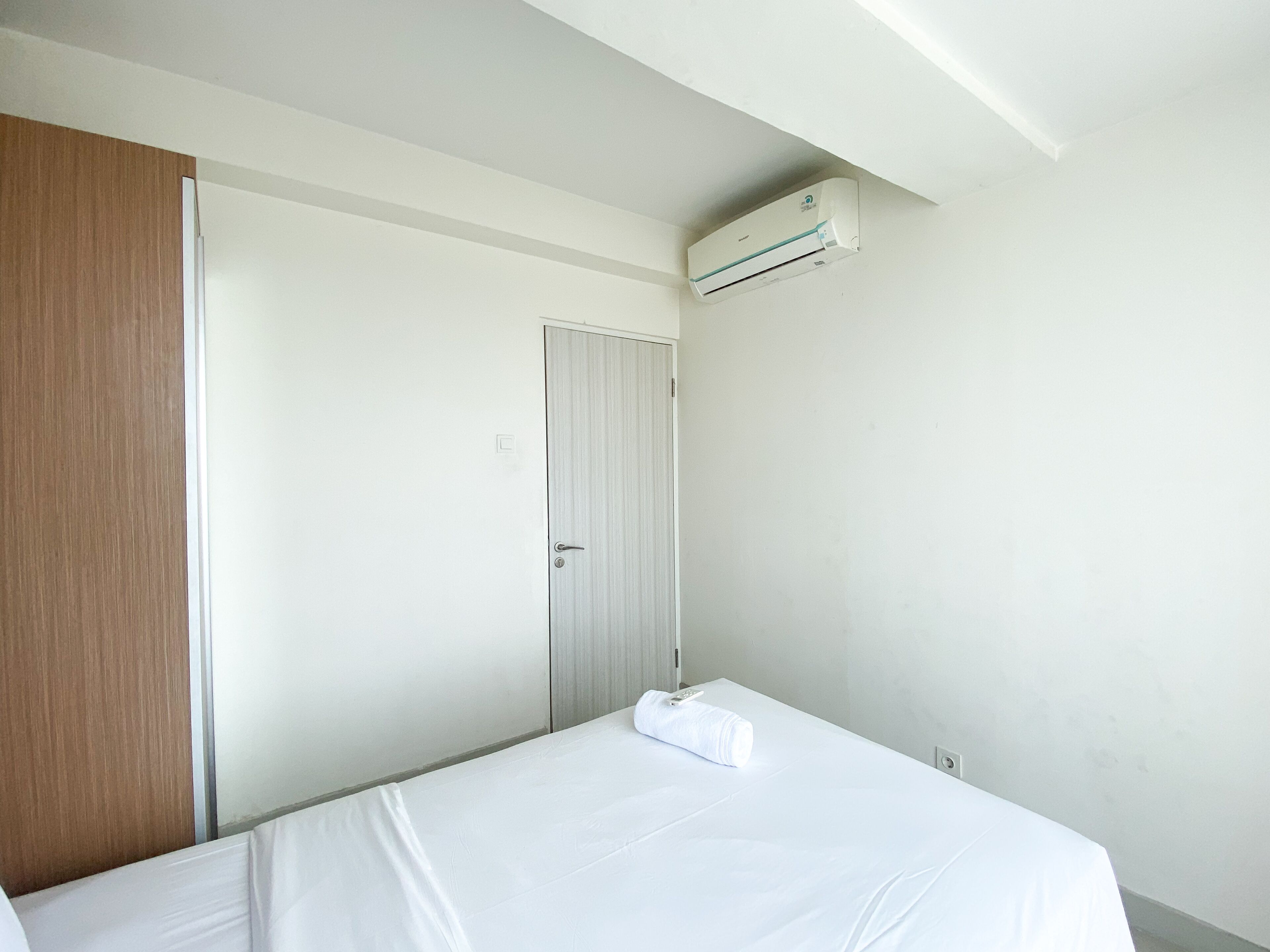 Una habitación de hotel con una cama, un armario de madera, una puerta y un equipo de aire acondicionado en la pared.