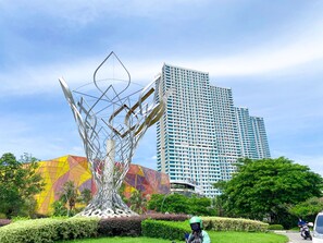 Une sculpture moderne dans un parc, avec un grand immeuble en arrière-plan.