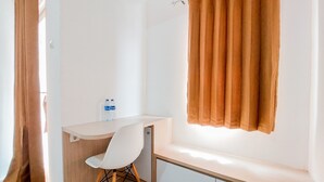 A small, well-lit room with a white desk, a white chair, and a window with brown curtains. - Modern Look Studio At Urbantown Serpong Apartment (South Tangerang)