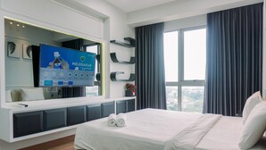 A modern hotel room with a large bed, a TV mounted on a white console, a window with curtains, and a city view.