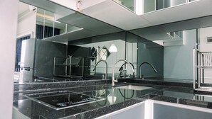 A modern kitchen with a large island, stainless steel appliances, and a mirrored backsplash.