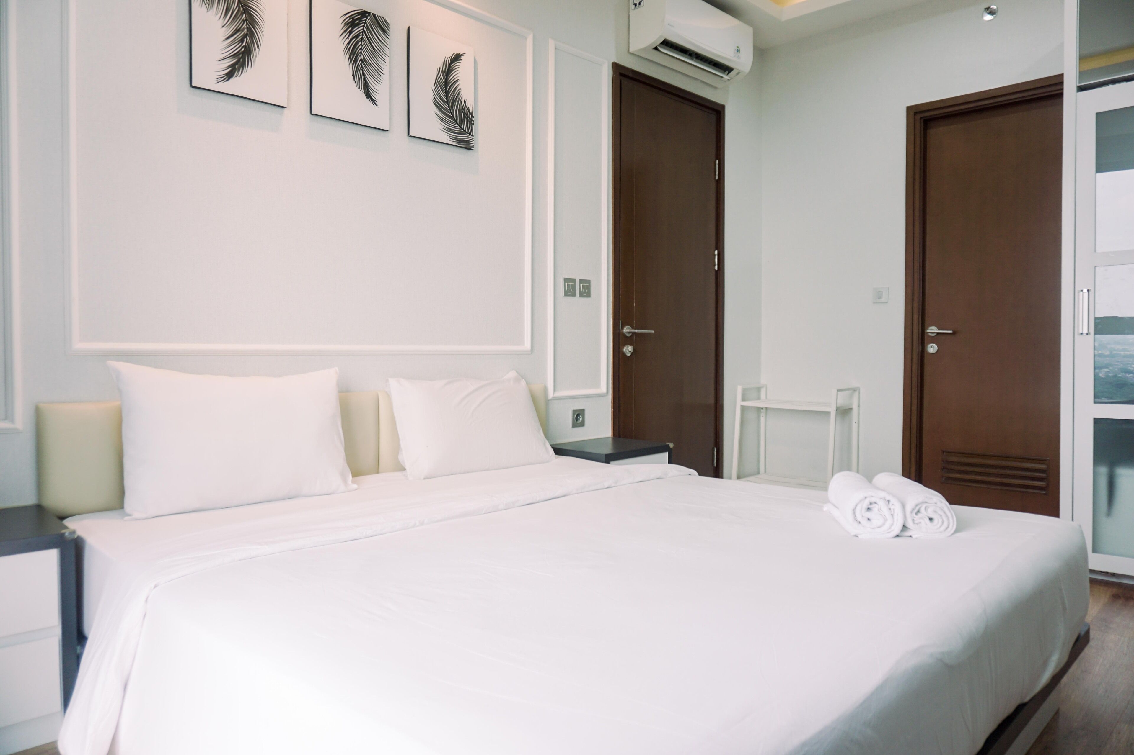 A hotel room with a large bed, two nightstands, a wardrobe, and a window.
