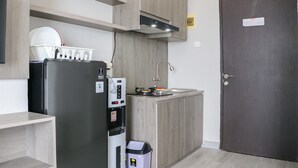 Et lille køkken med indbygget køleskab, kaffemaskine og vask.