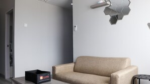 En moderne stue med en beige sofa, et træbord og en sekskantet vægdekoration.